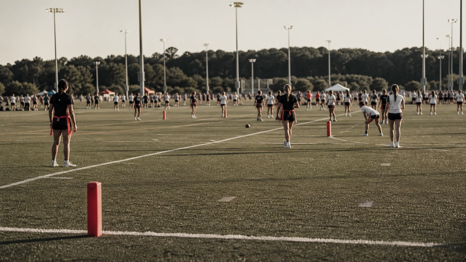Wide shot of a multi-field youth tournament complex with an end-zone pylon in the foreground.